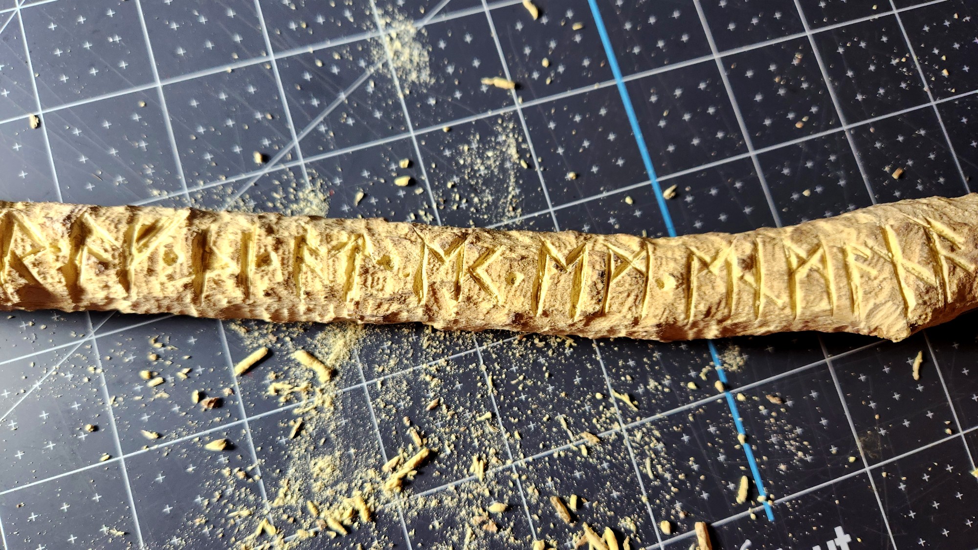 A length of stick with runes carved into it, looking something like a hack job with lots of sawdust and fragments of wood.