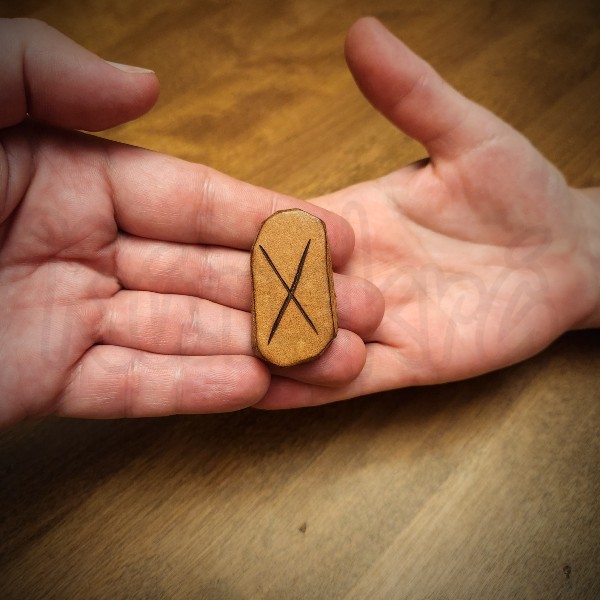 A man's hand reaching in from the left, placing the Gebo rune in a woman's hand on the right.