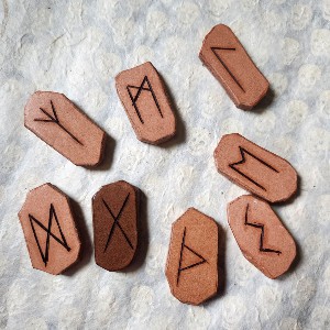 Several leather runes rest on a sheet of white paper. Gebo is considerably darker than the others.