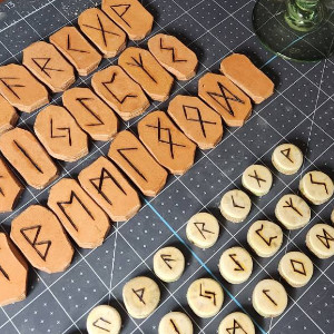 A worktable and cutting mat with two sets of runes on it, one in leather and the other made from a branch