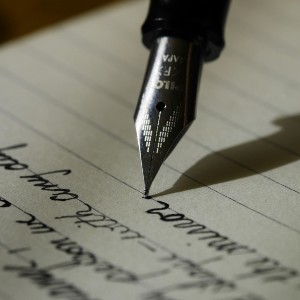 The nib of a fountain pen writing letters on a page of paper.