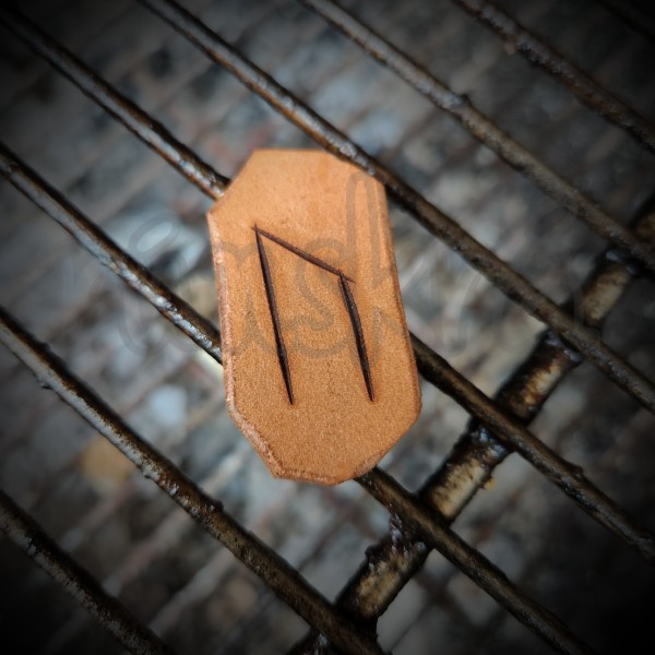 A leather tile with the rune Uruz burned into it. It rests upon the cooking grid of a greasy, inert grill.